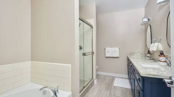 A modern bathroom with a glass-enclosed shower, a bathtub, and a vanity with a sink and mirror.