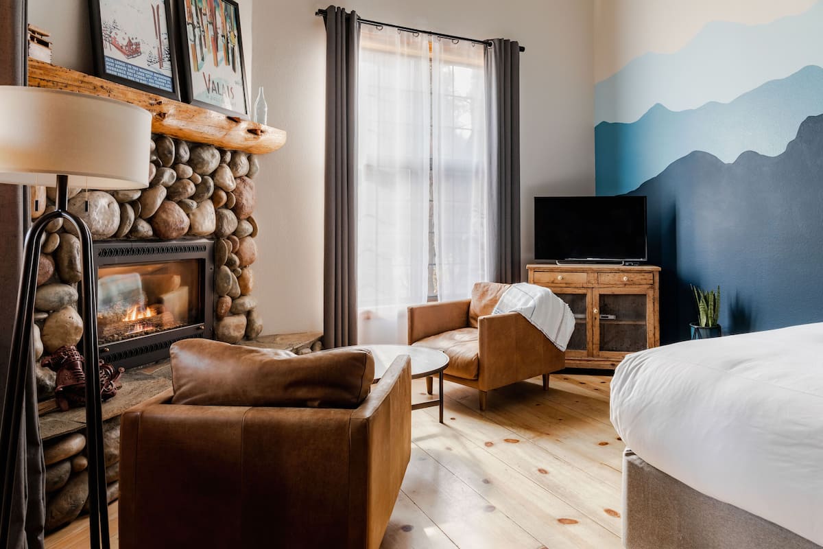 Een gezellige kamer met een stenen openhaard, leren bank en een bed.