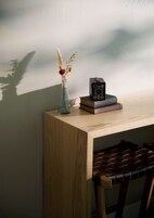 Un escritorio de madera con un florero de flores secas, una cámara y libros.