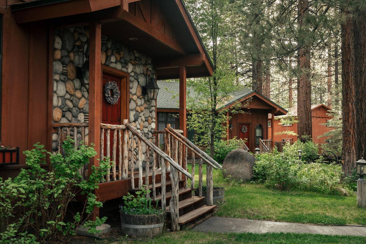 Een rustieke lodge met een stenen gevel, houten veranda en een stenen open haard.