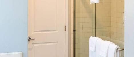 A bathroom with a white door, a glass shower enclosure, and a white bathtub.