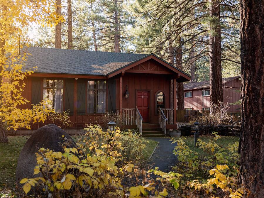 A cabin with a red door, a front porch, and a stone pathway leading to it.