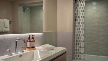 A modern bathroom with a large sink, a mirror, and a shower with a patterned curtain.