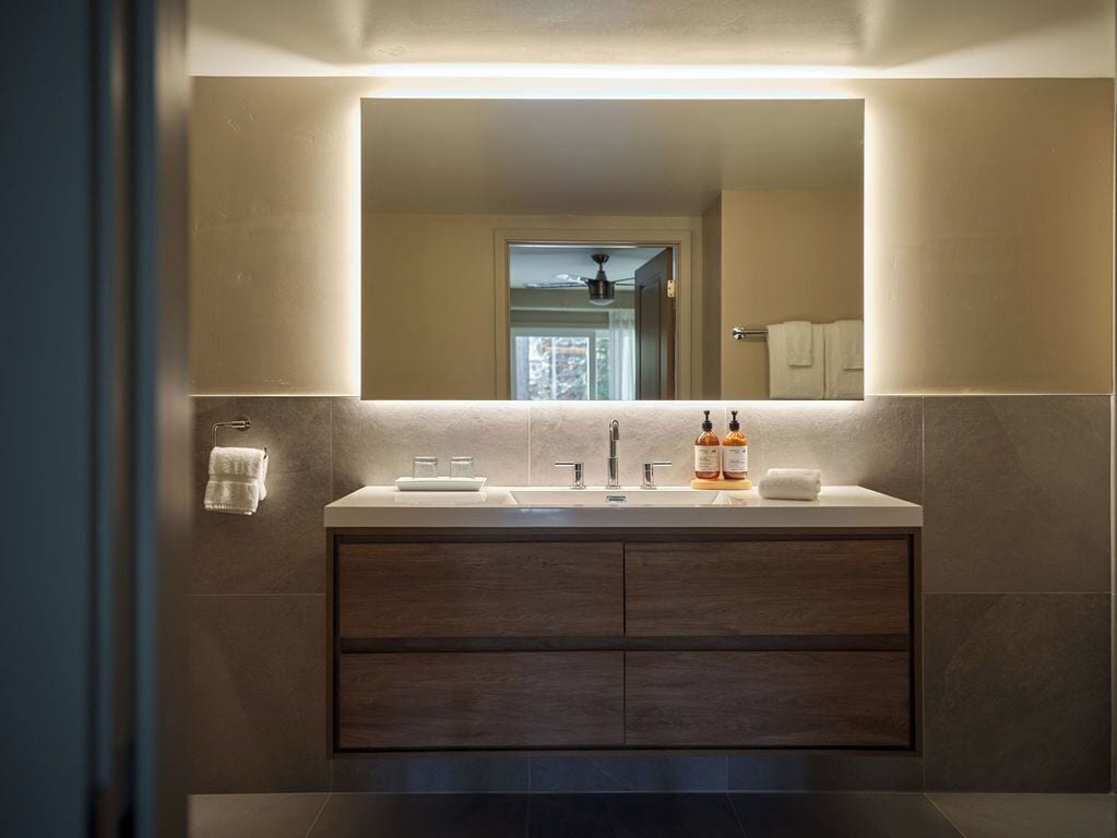 Un baño moderno con un espejo grande, dos lavamanos y un mueble tocador con cajones.
