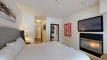 A hotel room with a large bed, a flat-screen TV, and a mirror.