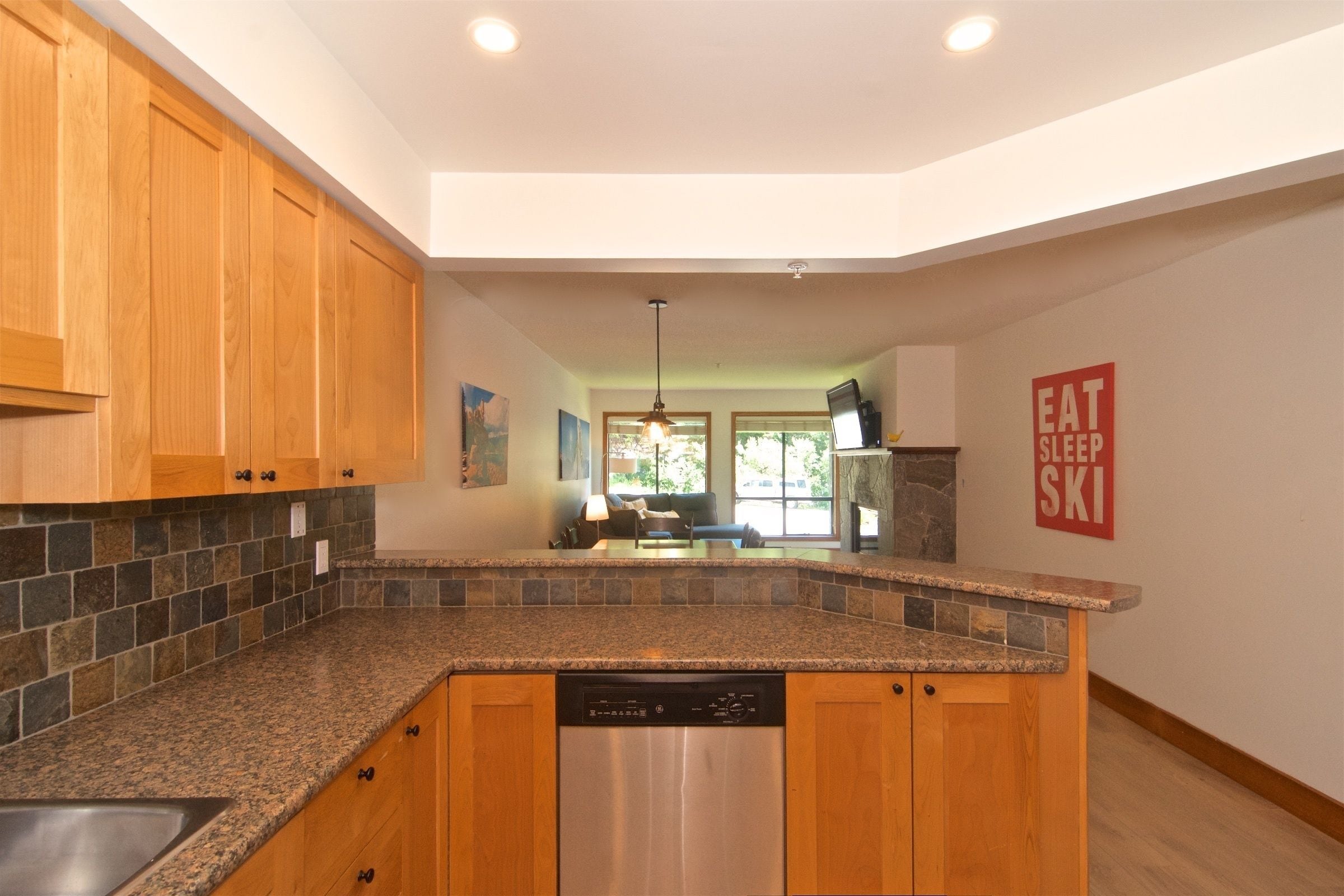 A kitchen with granite countertops, wooden cabinets, and a dishwasher.