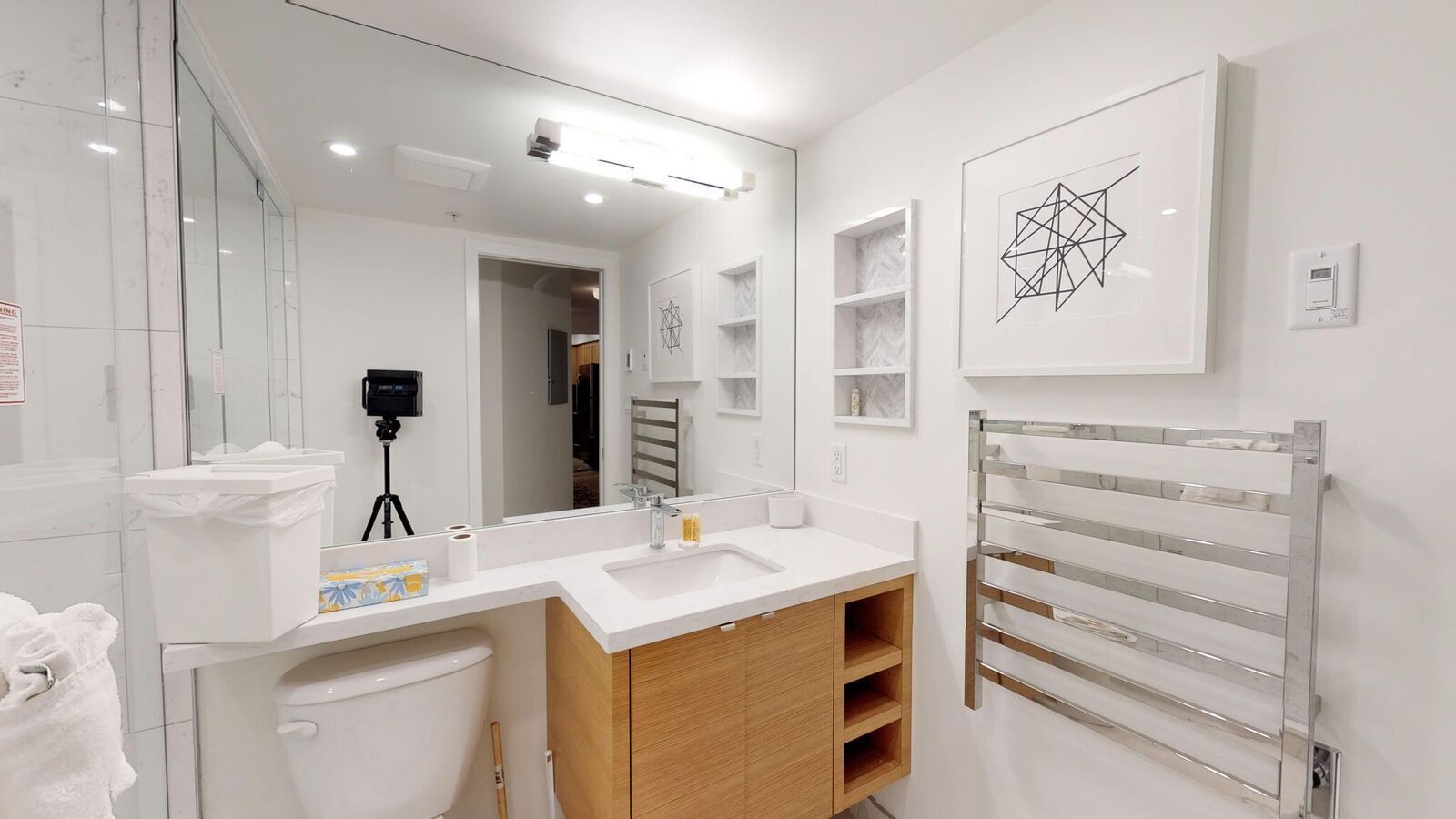 A modern bathroom with a white sink, wooden vanity, and a towel rack.