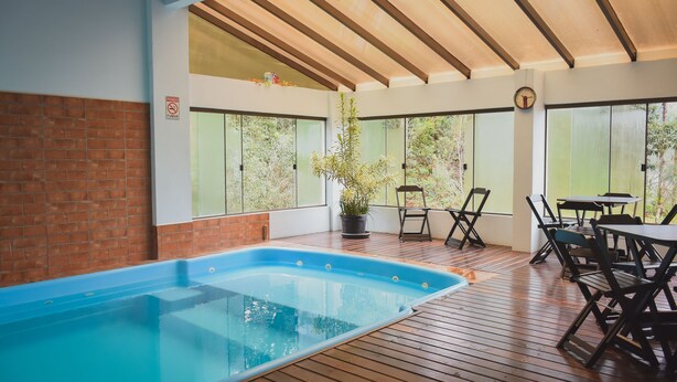 Zona de piscina con plataforma de madera, pared de ladrillo y planta en maceta.