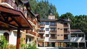 Un hotel de varios pisos con balcones, un espacio al aire libre cubierto y un estacionamiento.