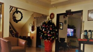 Un salón con un árbol de Navidad, un sillón de cuero marrón, una chimenea y un televisor.