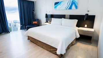 Habitación de hotel moderna con una cama grande, un escritorio y una silla. Se ve la ciudad a través de la ventana.