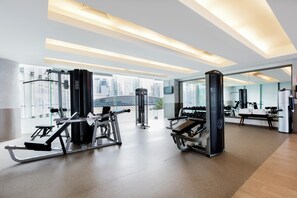 Een moderne sportschool met fitnessapparatuur, grote ramen en uitzicht op de stad.