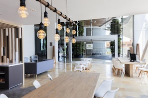 Een moderne kantoorruimte met een lange houten tafel, witte stoelen en hangende lampen.