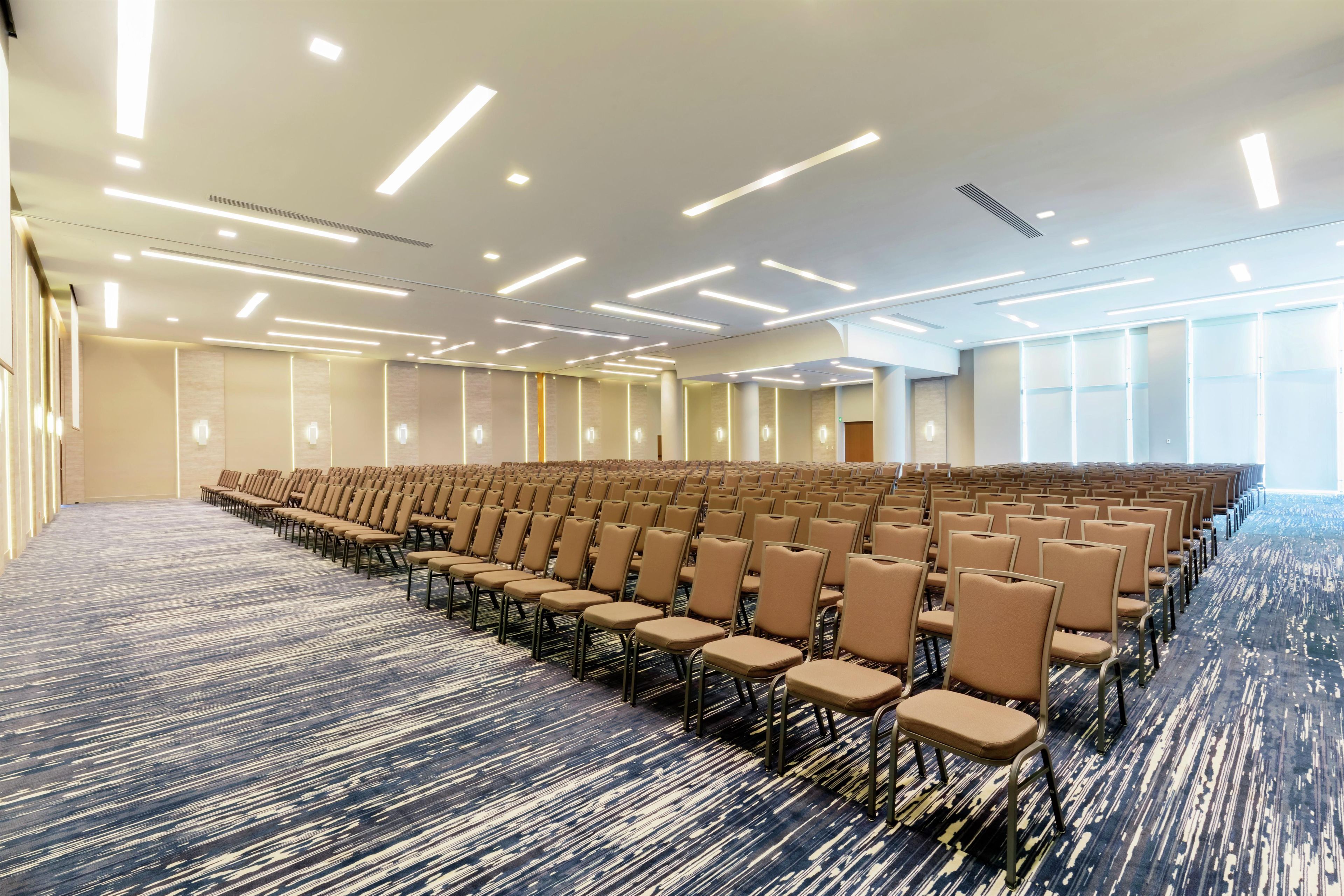 Une grande salle de conférence avec des rangées de chaises et un sol recouvert de moquette.