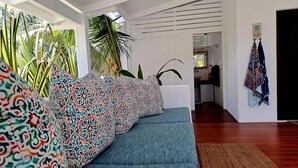 A modern living room with a blue sofa, patterned cushions, a brown rug, and a kitchen in the background. - Papaya Villa B&B  (Eton)