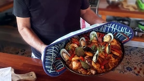 A person holding a large pan of seafood stew with clams and shrimp. - Papaya Villa B&B  (Eton)