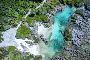 An aerial view of a tropical beach with clear turquoise waters, white sand, and lush greenery. - Papaya Villa B&B  (Eton)