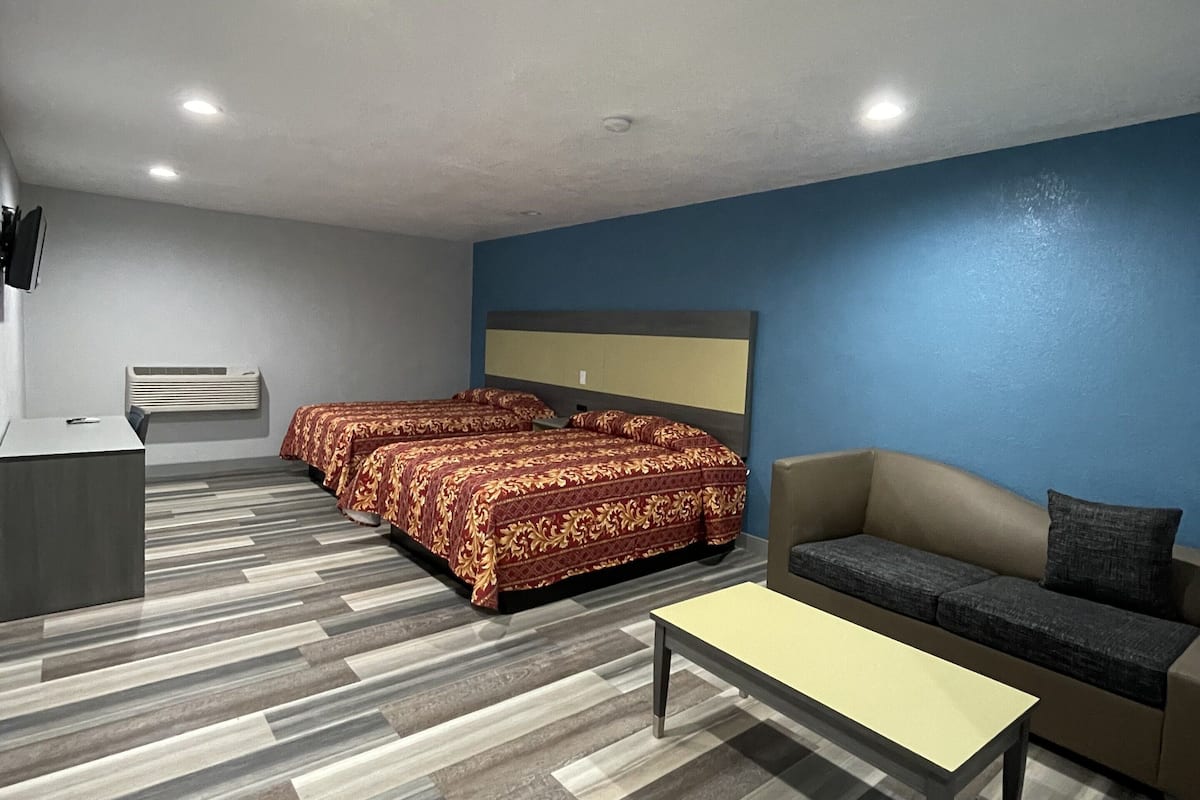 A hotel room with a bed, a sofa, a desk, and a coffee table.