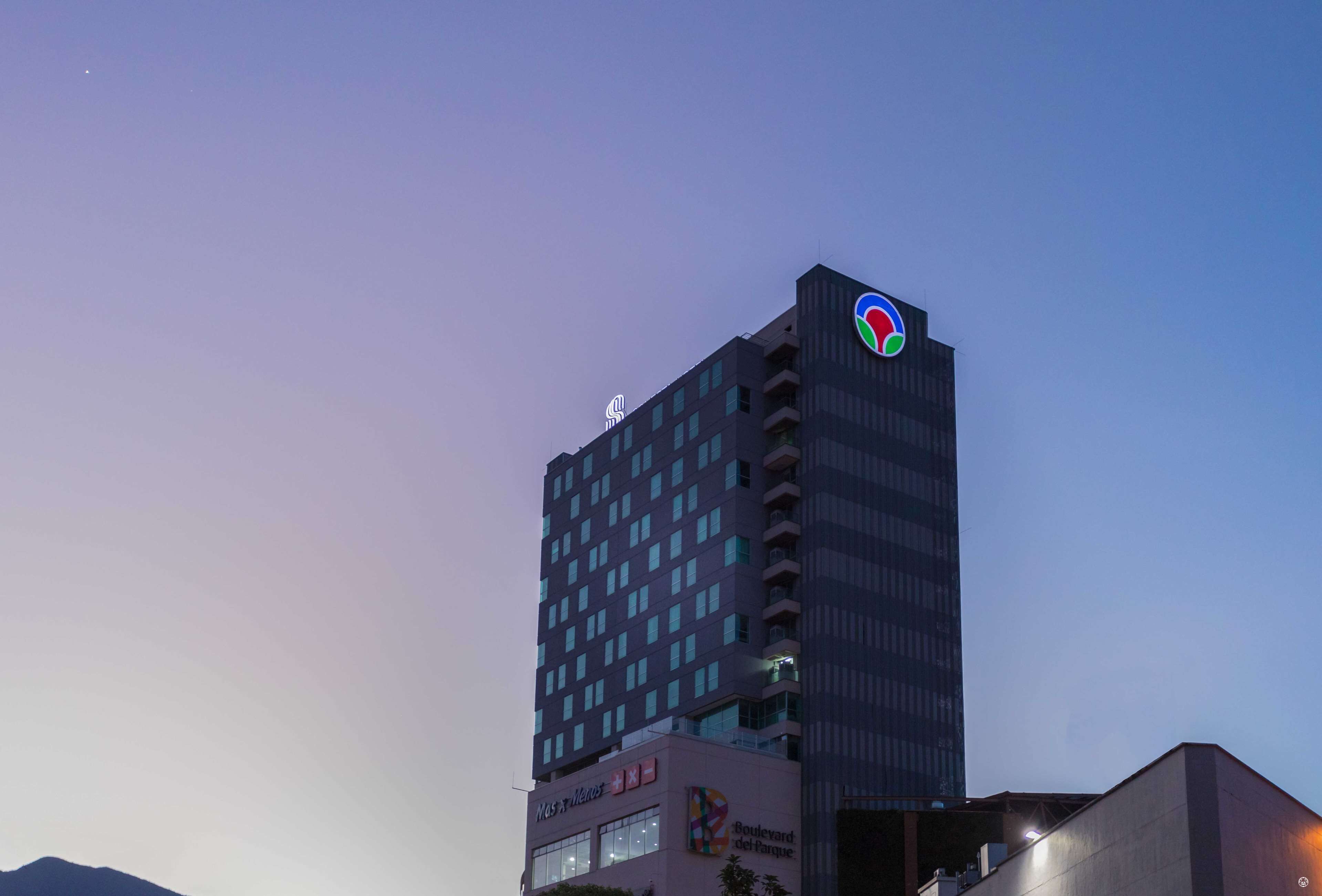 A tall hotel building with a prominent logo at the top.