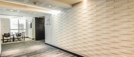 Un interior de oficina moderno con una pared estampada, un centro de negocios y una zona de recepción.
