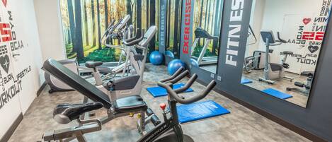 Un gimnasio con equipo cardiovascular, máquinas de pesas y pelotas de ejercicio.