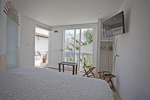 A bedroom with a large bed, a television mounted on the wall, a small table, and a chair. - Old Town Premium (Cartagena)