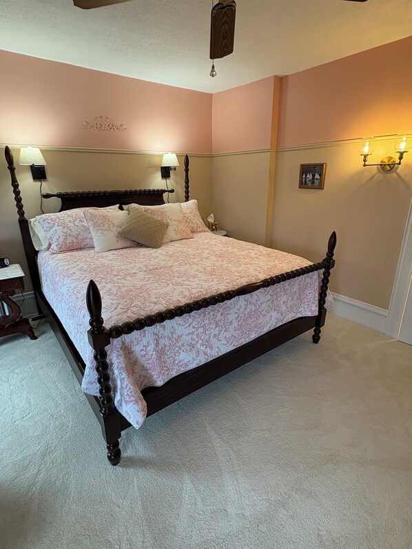Ein Schlafzimmer mit Himmelbett, zwei Nachttischlampen, einem Nachttisch und einer Wandleuchte.