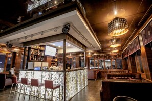 Zona de bar con mostrador de mármol, taburetes y un área de estar con sofá.