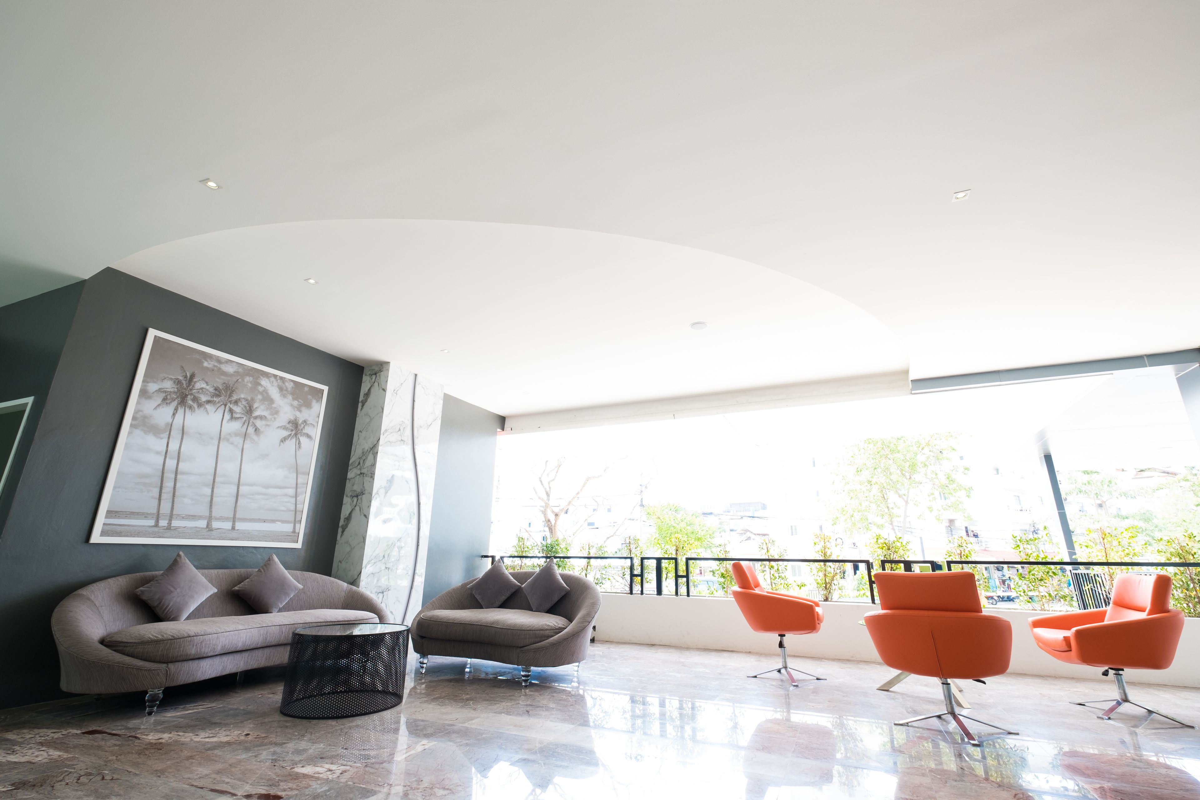 A modern living room with a grey sofa, a round coffee table, and orange chairs.