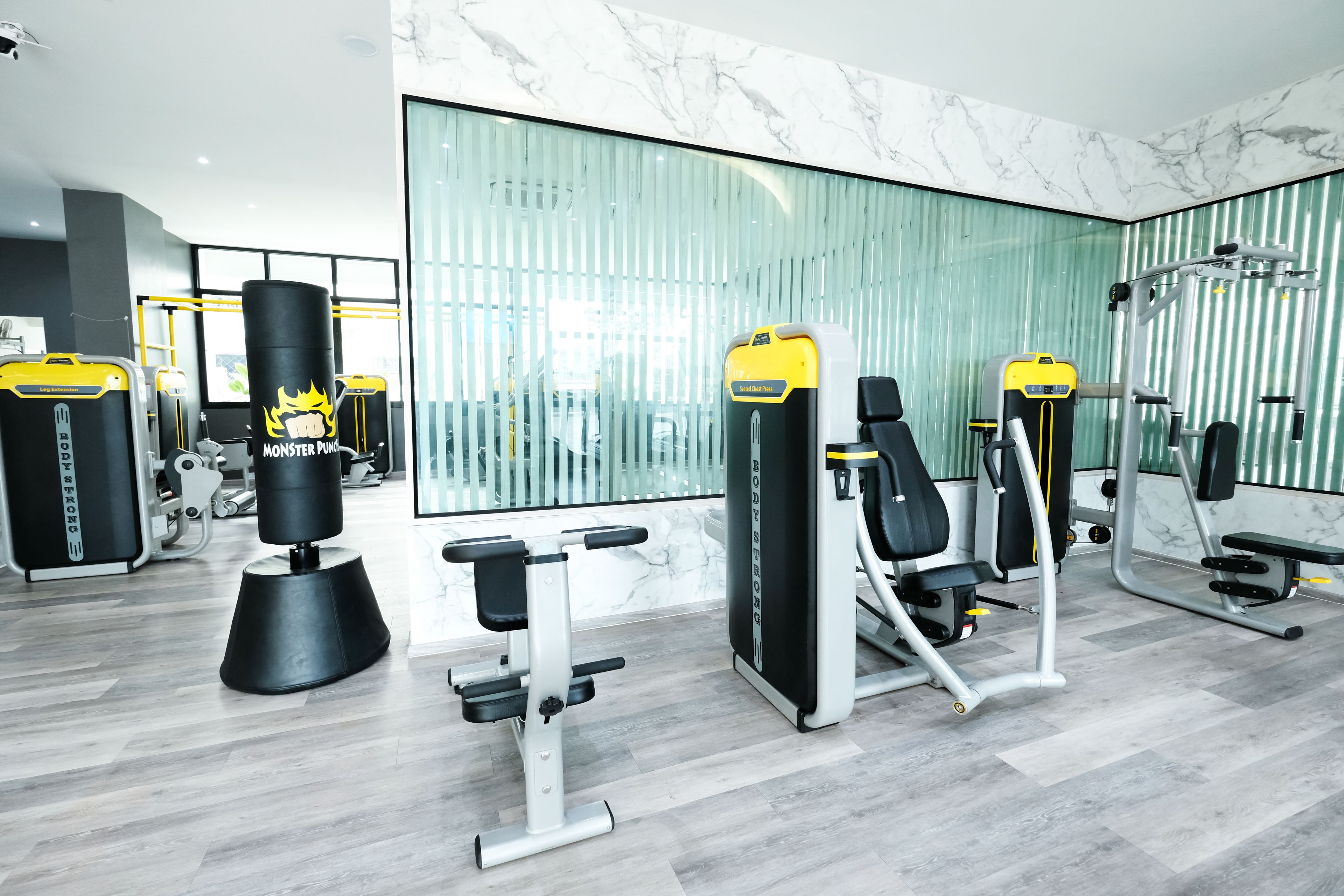 A modern gym with various exercise machines, large windows, and a marble floor.