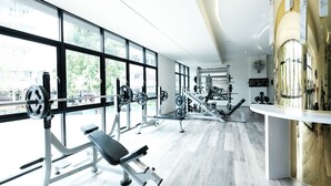 A modern gym with large windows, various exercise equipment, and a clean, light-colored floor. - P Plus Hotel (Pattaya)