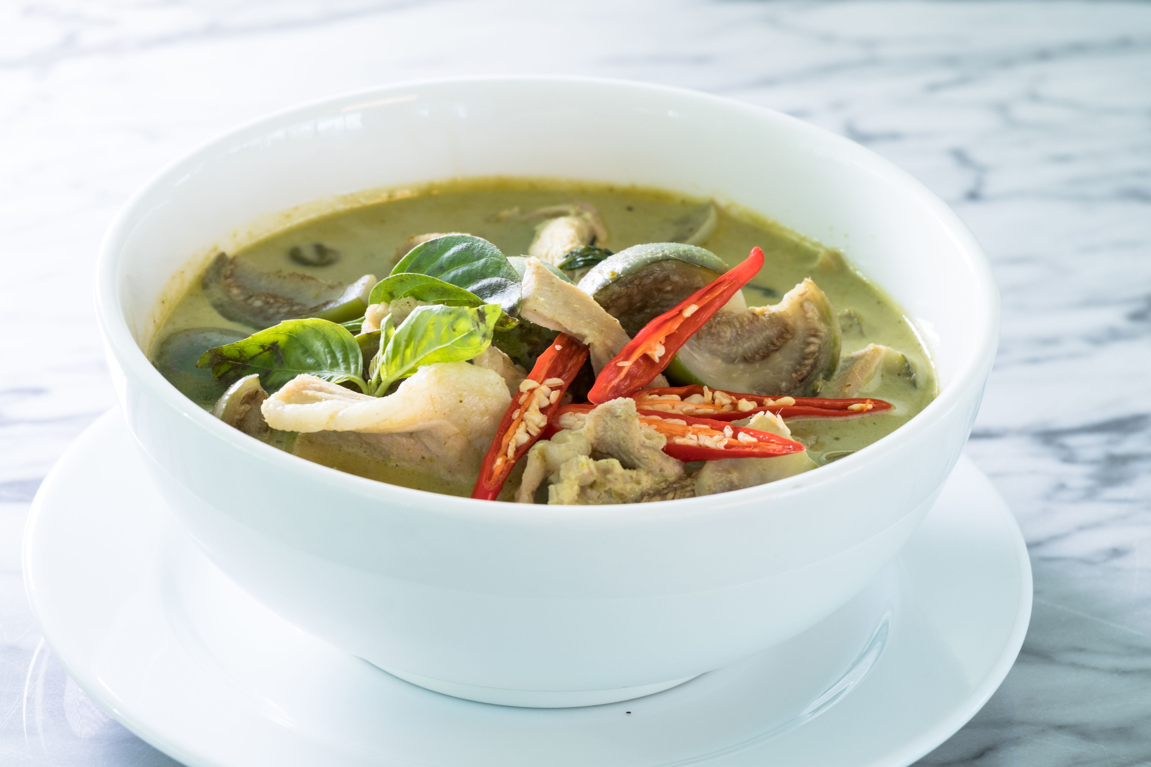 A bowl of soup with various ingredients on a white plate.