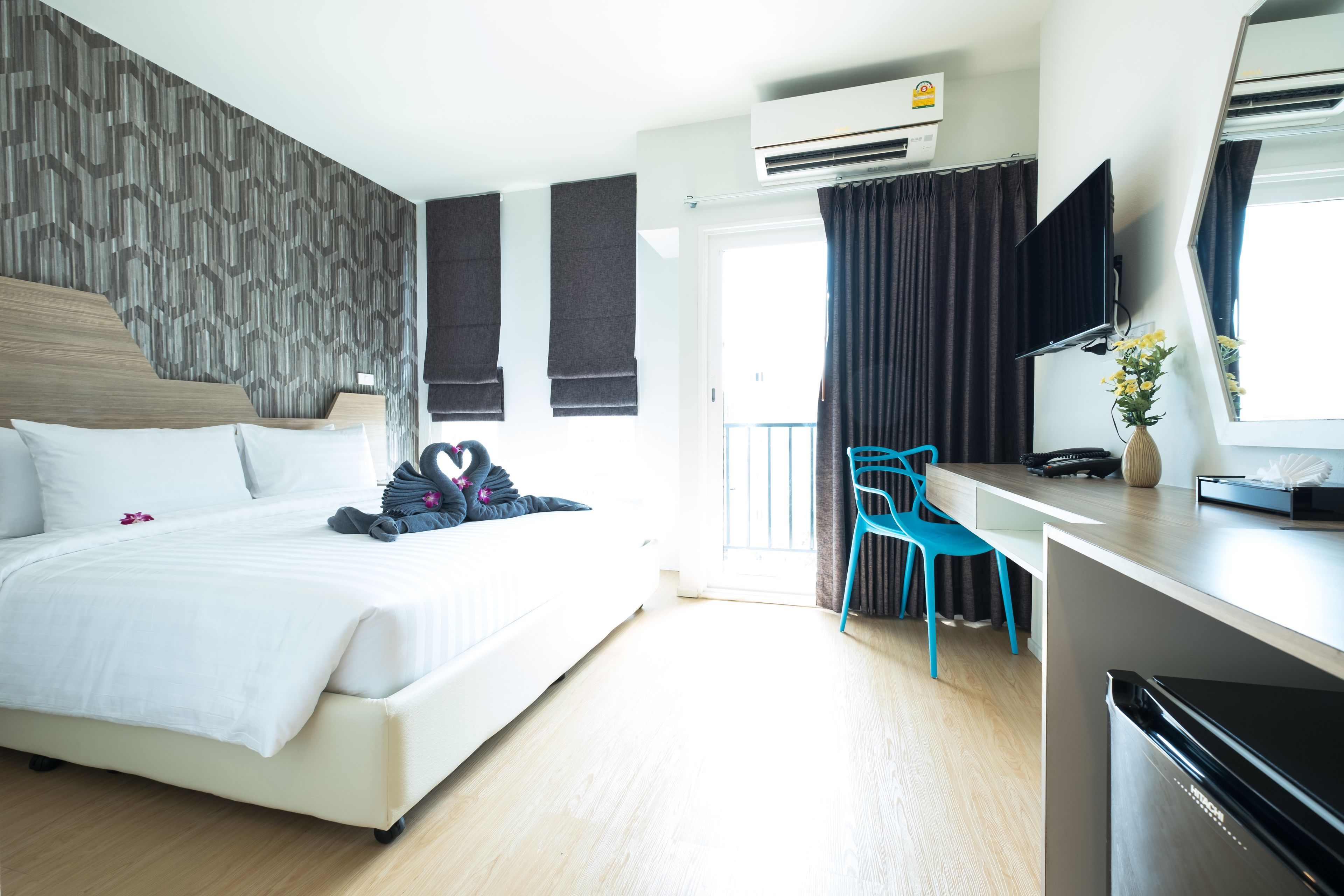 Ein modernes Hotelzimmer mit einem großen Bett, einem Schreibtisch, einem Sessel und einem Fernseher.
