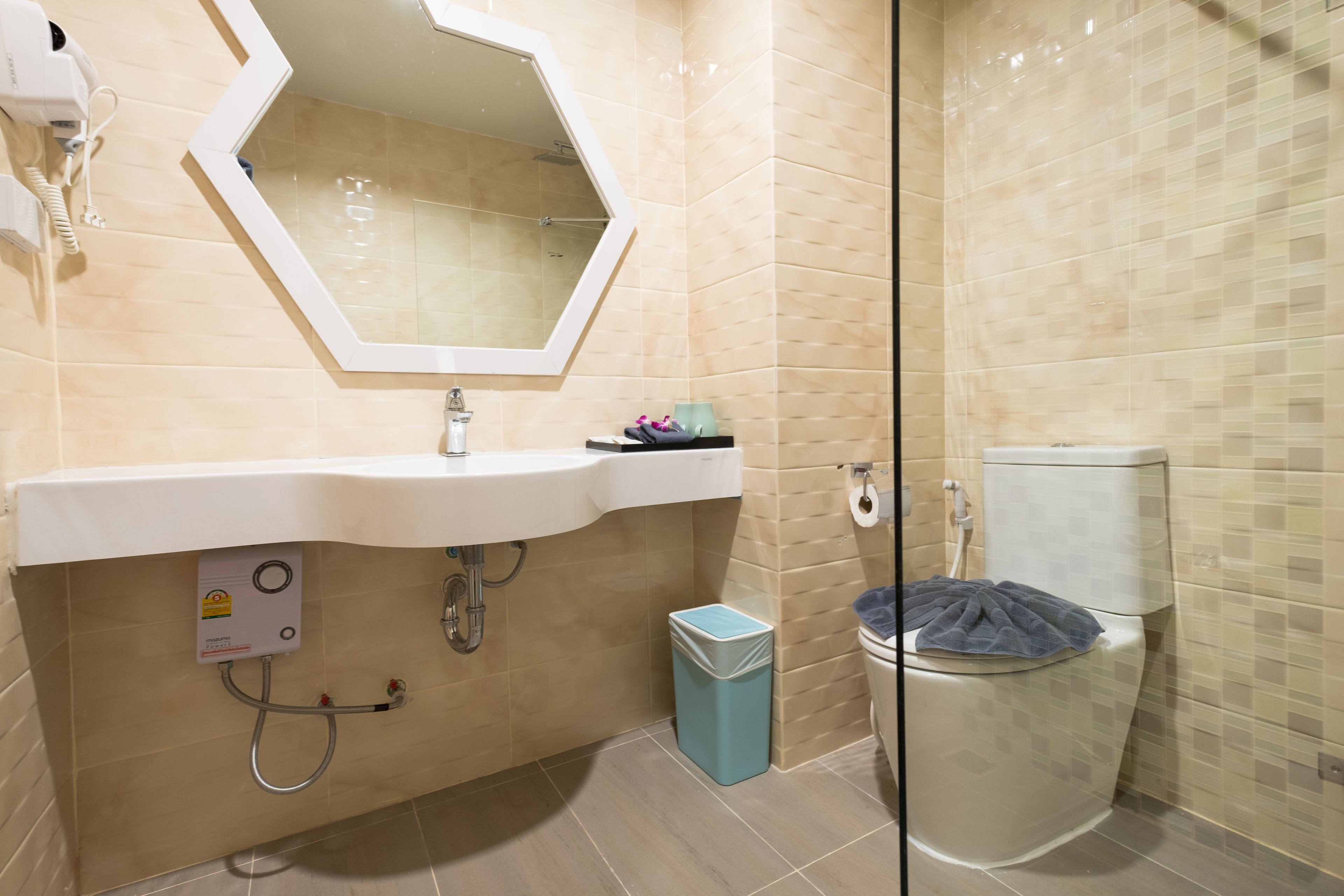 A bathroom with a white sink, a mirror, a toilet, and a trash bin.