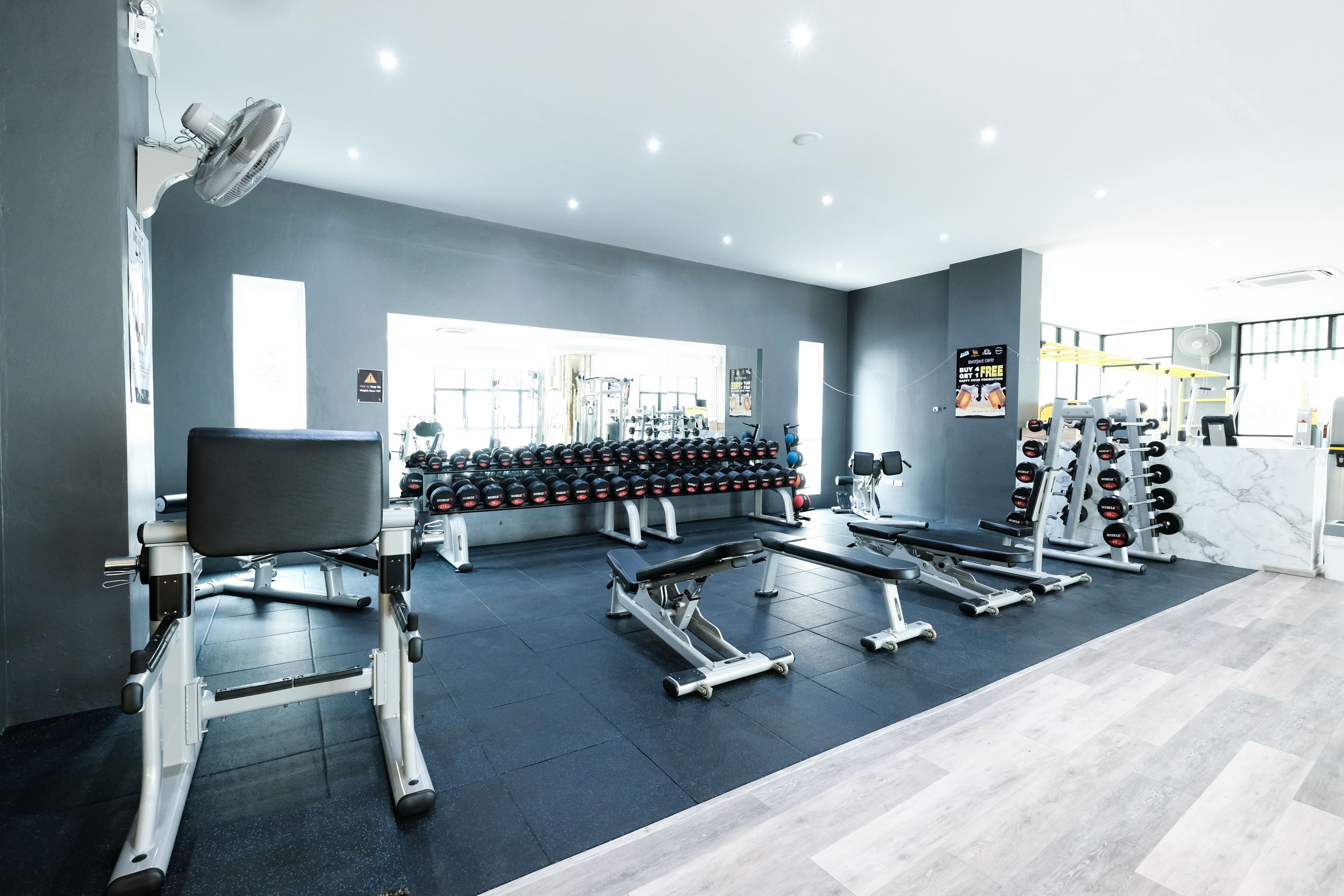 Une salle de sport moderne équipée de divers appareils d’exercice, notamment des haltères, des bancs et des machines de musculation.