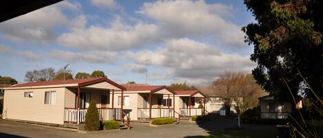 A row of mobile homes with a red roof, white railings, and a clear sky.