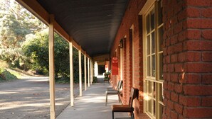 A covered outdoor seating area with brick walls and a row of chairs. - Miner's Retreat Motel (Ballarat East)