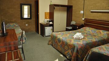 A hotel room with two beds, a desk, a chair, a small refrigerator, and a mirror on the wall.
