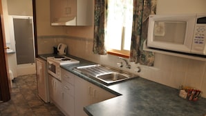 A kitchen with a sink, microwave, and cabinets. - Miner's Retreat Motel (Ballarat East)