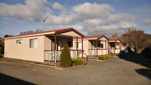 A row of mobile homes with a red roof, white trim, and a small porch with a railing. - Miner's Retreat Motel (Ballarat East)
