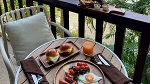 A breakfast setup on a balcony with a view of a swimming pool and lush greenery. - Sea Hills Resort (Patong)