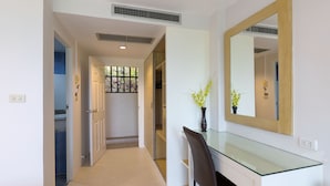 A hallway with a glass-top desk, a mirror, and a potted plant. - Sea Hills Resort (Patong)