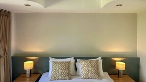 A neatly made bed with decorative towels, two bedside lamps, and patterned pillows. - Sea Hills Resort (Patong)