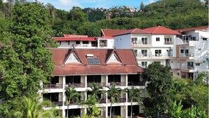 A resort with multiple buildings, a swimming pool, and lush greenery. - Sea Hills Resort (Patong)