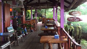 An outdoor cafe with wooden tables and benches, surrounded by greenery. - Baansiesom Private Pool Villa (Pranburi)