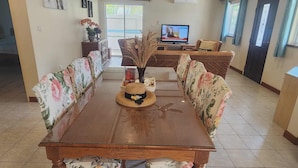 A dining area with a wooden table and floral upholstered chairs, a television, and a decorative vase. - Baansiesom Private Pool Villa (Pranburi)