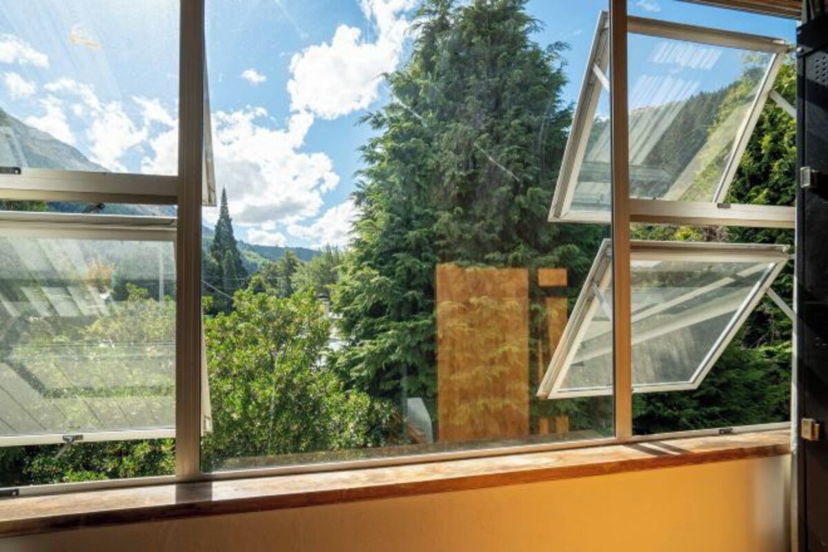A window with a view of a forest and mountains.