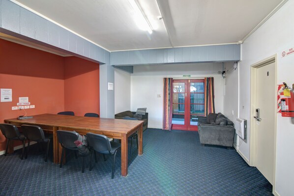 Una sala de conferencias con una mesa de madera, sillas, un sofá y una puerta con extintor.