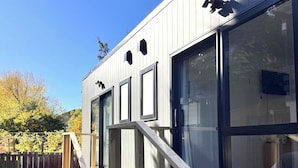 A modern building with large windows, a wooden staircase, and a metal railing. - The Flaming Kiwi Backpackers (Queenstown)