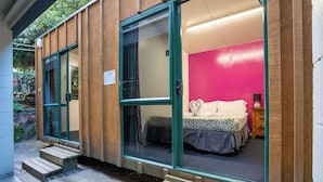A modern room with a bed, a nightstand, and a window. - The Flaming Kiwi Backpackers (Queenstown)